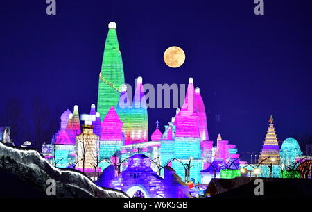 Illuminata di sculture di neve per il durante il XIX Cina Harbin ed al Mondo del Ghiaccio e della neve sono visti contro il sangue "upermoon' in cielo nella città di Harbin, nort Foto Stock