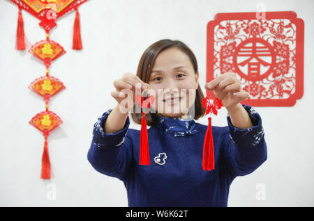 36-anno-vecchio artigiano cinese Liang Ying, un ereditiere di carta-talee, mostra una coppia di orecchini realizzati in carta-taglio di creato da se stessa nel suo stu Foto Stock