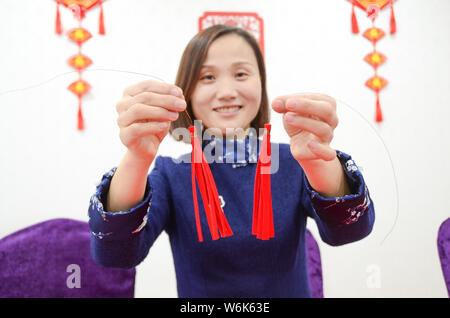 36-anno-vecchio artigiano cinese Liang Ying, un ereditiere di carta-talee, mostra una coppia di orecchini realizzati in carta-taglio di creato da se stessa nel suo stu Foto Stock