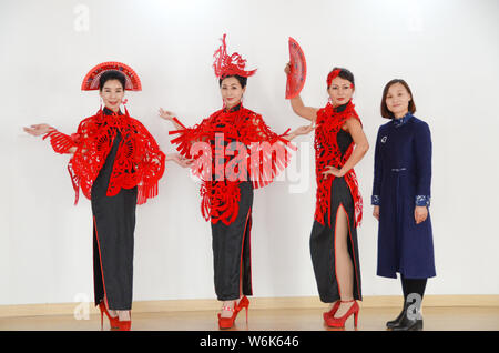 36-anno-vecchio artigiano cinese Liang Ying, a destra, un erede di carta-talee, pone per le foto con i modelli da indossare gli accessori di testa, mantelli, e orecchio Foto Stock