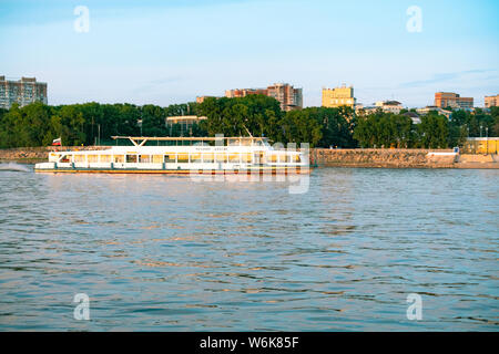 Vista della città di Khabarovsk dal fiume Amur. Il paesaggio urbano di sera al tramonto Foto Stock