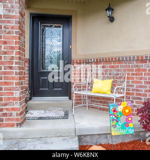 Portico quadrato con panchina di una casa con il vetro della porta vetrata e concrete e un muro di mattoni Foto Stock