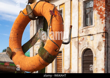 Grungy ciambella arancione montato sulla costa vicino a Porto Vecchio edifici a San Pietroburgo, Russia Foto Stock