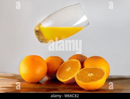 Un bicchiere di succo di arancia sopra le arance. Tagliata, agrumi freschi. Un tavolo di legno. Foto Stock