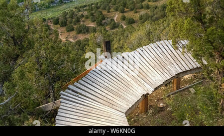 Panorama fino in prossimità di un ponte di legno nel mezzo di alberi e della curvatura lungo il pendio della foresta Foto Stock