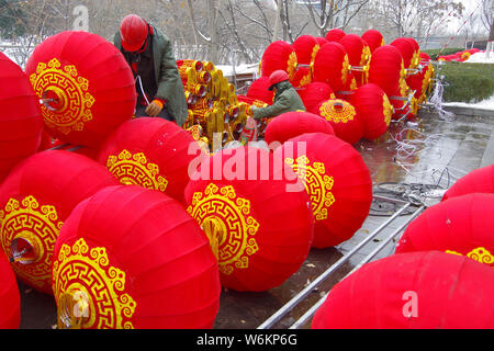 Un lavoratore cinese riaggancia lanterne rosse per celebrare la prossima festa della primavera o il nuovo anno cinese (anno del cane) su una strada a Xi'an City, Foto Stock