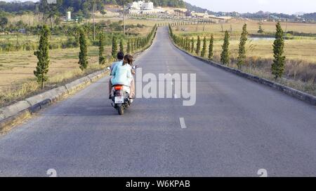 Pattaya, Tailandia - 18 Maggio 2019: giovane in sella motocicletta sulla strada rurale. Stock. Vista superiore del motociclista di equitazione e di sua moglie. Viaggio romantico. Su Foto Stock