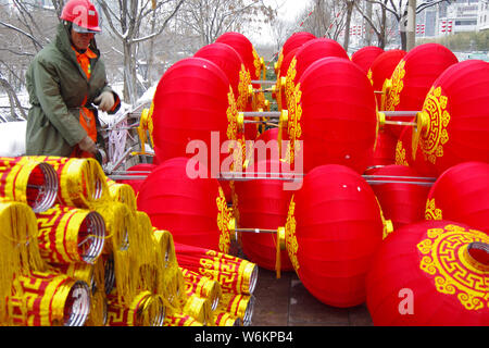 Un lavoratore cinese riaggancia lanterne rosse per celebrare la prossima festa della primavera o il nuovo anno cinese (anno del cane) su una strada a Xi'an City, Foto Stock