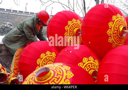 Un lavoratore cinese riaggancia lanterne rosse per celebrare la prossima festa della primavera o il nuovo anno cinese (anno del cane) su una strada a Xi'an City, Foto Stock