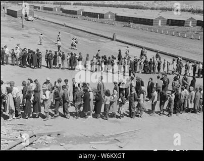 San Bruno, California. Il gruppo di questo centro è stato aperto per due giorni. Bus-carico dopo il bus-carico di . . .; Portata e contenuto: tutta la didascalia per questa fotografia si legge: San Bruno, California. Il gruppo di questo centro è stato aperto per due giorni. Bus-carico dopo il bus-carico delle persone evacuate di ascendenza giapponesi stanno arrivando in questo giorno dopo il passaggio attraverso le procedure necessarie, sono guidate ai quarti a loro assegnata in caserma. Solo un mess hall era operativo oggi. Fotografia mostra la line-up di neo arrivato agli sfollati al di fuori di questo pasticcio hall a mezzogiorno. Nota caserme in background, jus Foto Stock