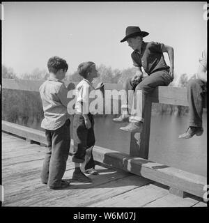 San Joaquin Valley, California. Contratto di lavoro. Un paio di li'l fellers dalle famiglie che vivono nel lavoro del contraente di camp sono di accattonaggio BB per una pistola ad aria compressa da un sedicenne membro dell'equipaggio Copus che come i loro genitori è attesa per la promessa di lavorare per iniziare Foto Stock