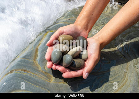 Palms tenere un mucchio di pietre in riva al mare Foto Stock