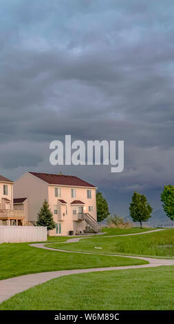 Verticale facciata di Casa che si affaccia su un ampio campo di verde con un percorso lastricato e stagno Foto Stock