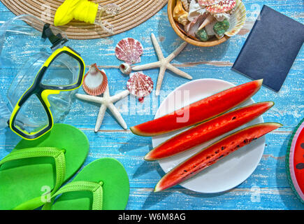 Piatto Topview lay out di anguria a fette decorate con attrezzature subacquee e conchiglia di mare posto su un blu tavolo in legno dal mare,Vacanza Estate concetto. Foto Stock