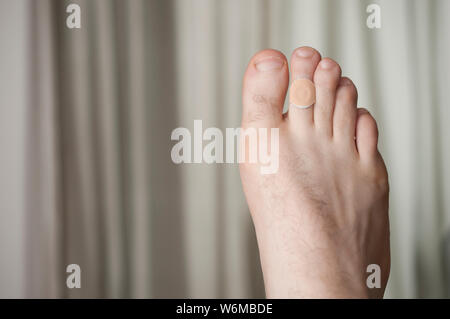 L'uomo piedi con il mais remover pad sul secondo dito Foto Stock