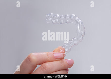 Close-up di donna di mano azienda trasparente delle traverse di plastica su sfondo grigio Foto Stock