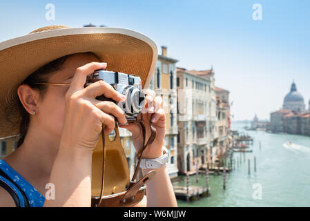 Turista femminile indossando cappello di paglia di scattare le foto sulla fotocamera in Canal Grande a Venezia Foto Stock