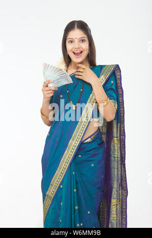 South Indian woman holding banknotes and looking surprised Stock Photo