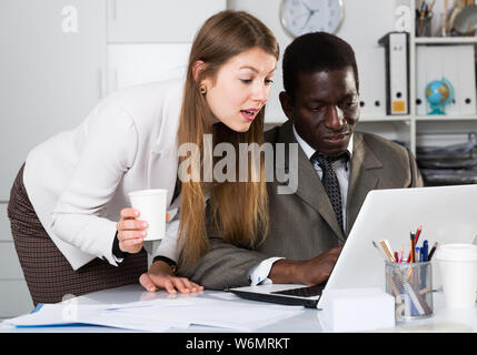 Gentili colleghi che lavorano insieme e flirtare al posto di lavoro in un ufficio moderno Foto Stock