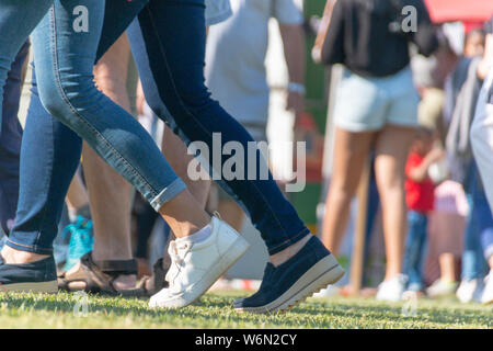 Una vista ravvicinata della metà inferiore dei popoli gambe camminando attorno ad un verde campo garss Foto Stock