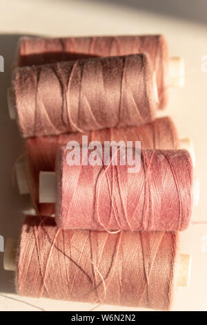 Una vista ravvicinata di cinque rosa bobine di cotone in una pila su un sfondo isolato Foto Stock
