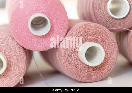 Una vista ravvicinata di cinque rosa bobine di cotone in una pila su un sfondo isolato Foto Stock