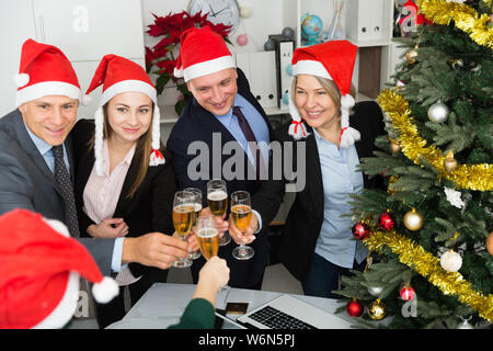 Gruppo di colleghi felice in cappelli di Babbo Natale festeggiano il Natale in ufficio Foto Stock
