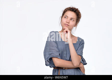 Bella giovane donna con Dreadlocks nel vestito blu pensando alla ricerca di imaging i suoi piani per il futuro. Isolato su sfondo bianco Foto Stock