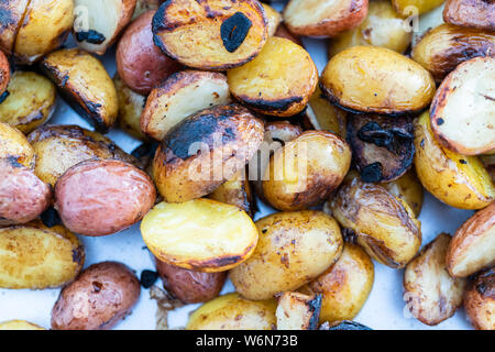 Grigliare piccole patate con fettine di aglio su una piscina grill a gas. Foto Stock