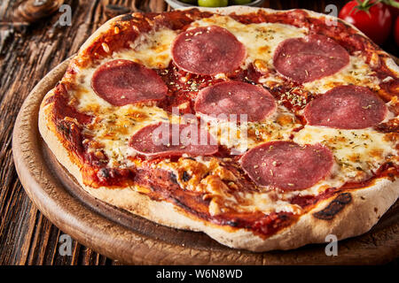 Chiudere fino a fiamma-grigliate di crosta di pizza italiana condito con pomodoro, mozzarella e fette di salsiccia per pizza piccante Salsiccia Foto Stock
