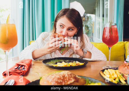 Giovane donna mangiare hamburger vegetariano. Vista posteriore. Foto Stock