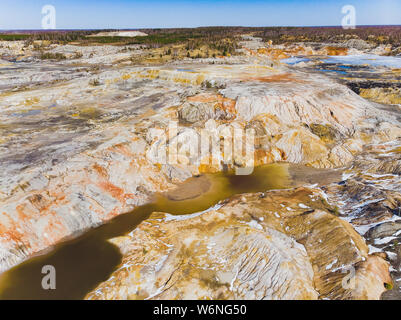 Argilla cava aperta Mars paesaggio con acqua di colore arancione. Abbandonato il Rock Texture porcellana vecchia miniera di buca di Ural. Erosione Crack Hill superficie desertica. Foto Stock