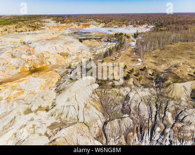 Argilla cava aperta Mars paesaggio con acqua di colore arancione. Abbandonato il Rock Texture porcellana vecchia miniera di buca di Ural. Erosione Crack Hill superficie desertica. Foto Stock