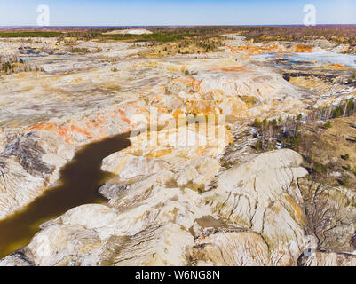 Argilla cava aperta Mars paesaggio con acqua di colore arancione. Abbandonato il Rock Texture porcellana vecchia miniera di buca di Ural. Erosione Crack Hill superficie desertica. Foto Stock