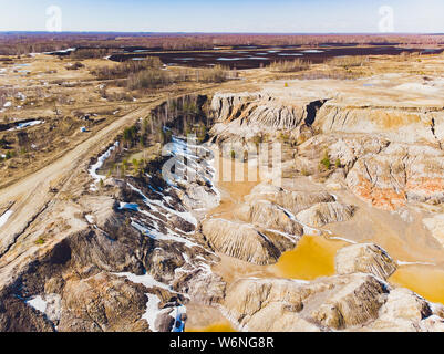 Argilla cava aperta Mars paesaggio con acqua di colore arancione. Abbandonato il Rock Texture porcellana vecchia miniera di buca di Ural. Erosione Crack Hill superficie desertica. Foto Stock