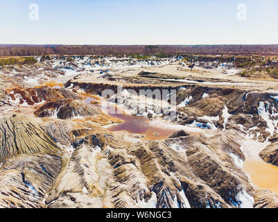 Argilla cava aperta Mars paesaggio con acqua di colore arancione. Abbandonato il Rock Texture porcellana vecchia miniera di buca di Ural. Erosione Crack Hill superficie desertica. Foto Stock