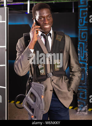 Ritratto di African American uomo nel business suit parlando al telefono mobile a laser camera tag Foto Stock