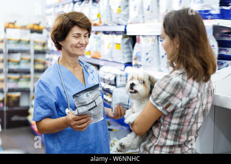 Donna matura consulenza veterinaria client femmina con graziosi havanese circa pet mangime secco in clinica Foto Stock