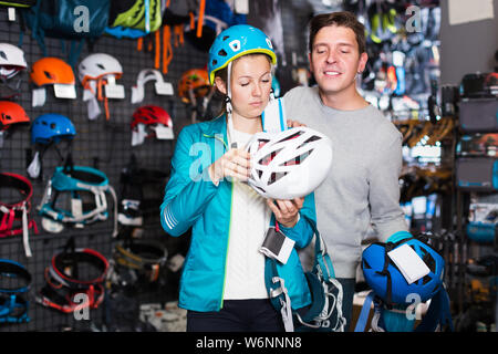 Positivo giovane uomo e donna nel negozio di sport la scelta di arrampicata attrezzature Foto Stock