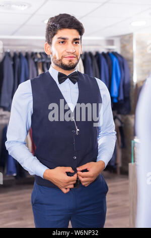 Ragazzo sta cercando sull'immagine scelta di fronte allo specchio in uomini shop. Foto Stock