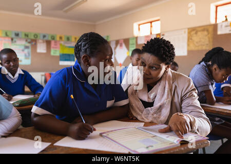 Insegnante aiutando gli scolari in una lezione presso una scuola comunale Foto Stock