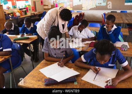 Insegnante aiutando gli scolari in una lezione presso una scuola comunale Foto Stock