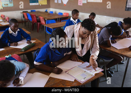 Insegnante aiutando gli scolari in una lezione presso una scuola comunale Foto Stock