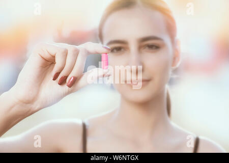 Bella donna con capelli scuri tiene in mano pillole colorate supplementi, Sport, vitamine, dieta, messa a fuoco selezionata Foto Stock