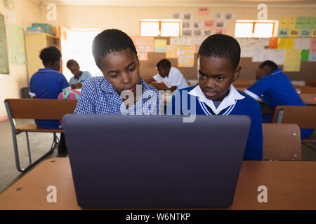 Scolari utilizzando computer portatile in una lezione presso una scuola comunale Foto Stock