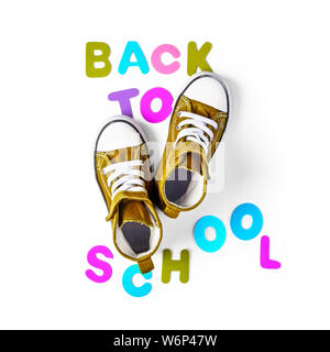 Si torna a scuola concetto con il vecchio sneakers. Bambini sport scarpe e lettere colorate disposizione isolata su sfondo bianco percorso di clipping incluso. T Foto Stock