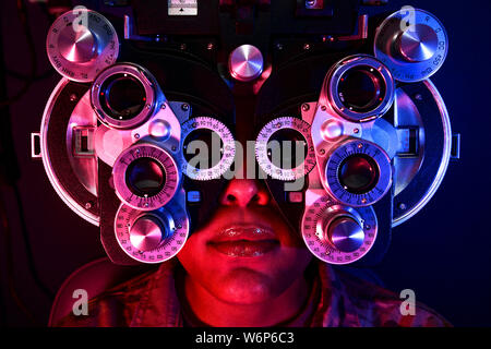 Una paziente femmina guarda attraverso un phoropter durante una visita oculistica sessione di formazione presso all'Aeroporto Internazionale di Pittsburgh riserva d'aria dalla stazione di Pennsylvania. La sessione di formazione insegnato optometria personale come usare correttamente un phoropter per determinare la prescrizione di occhiali di un paziente deve correggere la loro visione. Foto Stock