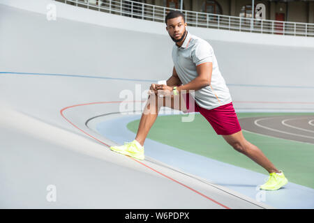 Calma e attraente giovane sportswear stiramento dei muscoli Foto Stock