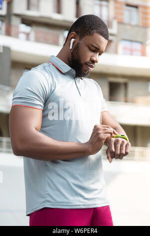 Sano giovane uomo che guarda il suo tracker fitness Foto Stock