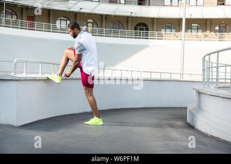 Runner maschio in sneakers tirando su la sua calza Foto Stock